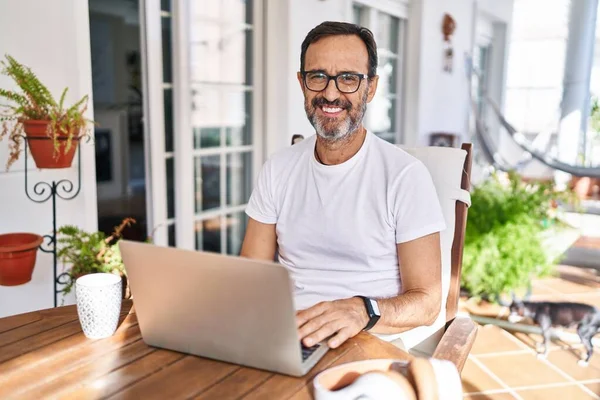 顔に幸せとクールな笑顔で自宅でコンピュータのラップトップを使用している中年の男性 運のいい人 — ストック写真