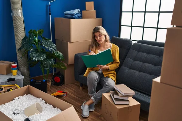 Young Blonde Woman Sitting Sofa Writing Book New Home — Stock Photo, Image