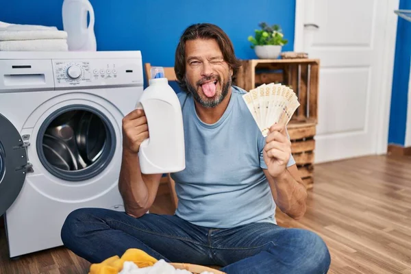 ハンサムな中年男節約お金の洗濯洗剤ステッキング舌アウト幸せとともに面白い式 — ストック写真