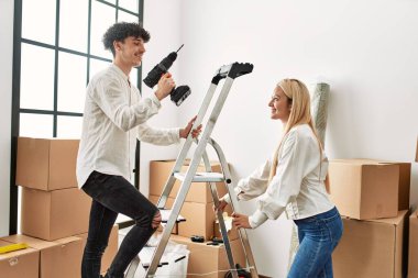 Yeni evinde elinde matkapla merdivenleri çıkan bir adam..