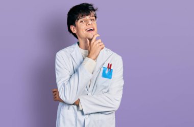 Yakışıklı hippi, doktor üniforması giyen, gülümseyen kollarını kavuşturup, elleri çenesinde kameraya bakan genç adam. Olumlu düşünmek. 