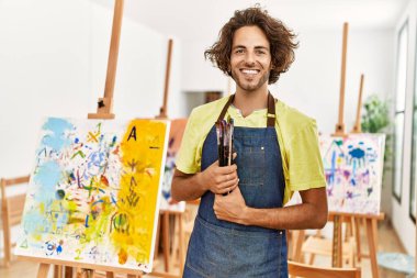 Genç İspanyol sanatçı gülümsüyor. Resim stüdyosunda fırça tutarken mutlu..