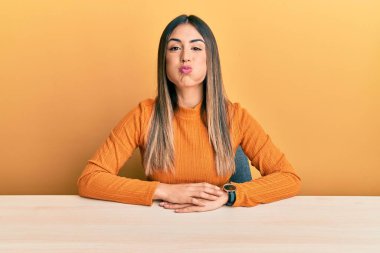 Masada oturan, sıradan kıyafetler giyen, komik yüzlü İspanyol bir kadın. Havayla şişmiş ağız, çılgın bir ifade.. 