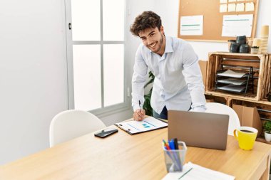 Ofiste çalışırken gülümseyen genç İspanyol işadamı..