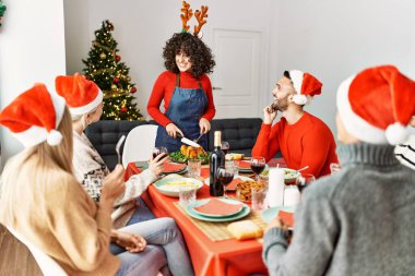 Mutlu bir şekilde gülümseyen bir grup genç kadın evde servis etmek için kızarmış hindi kesiyor..