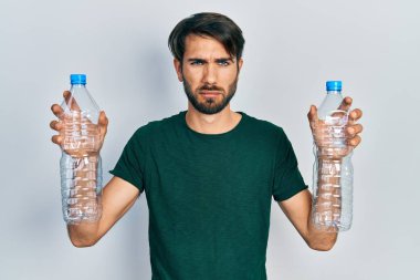 Plastik şişeleri geri dönüşüm için tutan genç bir İspanyol bunalımlı ve üzüntülü, sinirli ve korkmuş bir şekilde ağlıyor. hüzünlü ifade. 