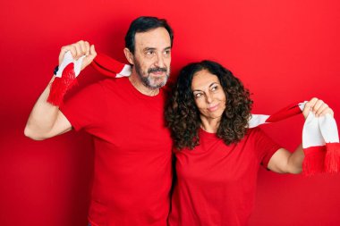 Orta yaşlı bir çift İspanyol kadın ve erkek eşarp takıyor futbol holigan tezahürat oyunu gülümsüyor ve diğer tarafa bakıyor.. 