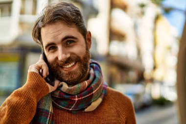 Beyaz sakallı bir adam güneşli bir günde telefonda konuşuyor.