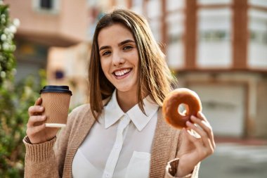 Genç İspanyol iş kadını gülümseyerek şehirde kahvaltı yapıyor..