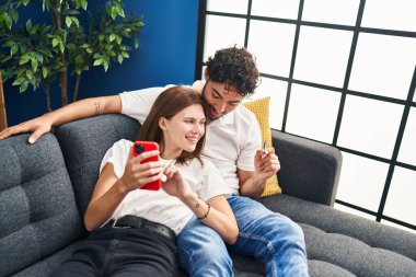 Kadın ve erkek evde akıllı telefon ve kredi kartı kullanıyor.