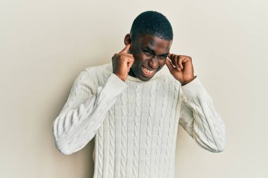 Genç Afro-Amerikan adam gündelik kıyafetler giyip yüksek sesli müzik sesi için kulaklarını parmaklarıyla kapatıyor. sağır kavramı. 