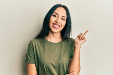 Yüzünde kocaman bir tebessüm olan, el ve parmaklarıyla kameraya bakan İspanyol tişörtü giyen genç kız.. 