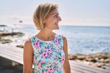 Orta yaşlı, güzel bir kadın. Deniz kenarında kendine güvenen.