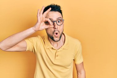 Günlük kıyafetler ve gözlük takan genç İspanyol adam şaşırmış yüz ifadesiyle şaşırmış, parmaklarından bakan gözler. İnançsız ifade. 