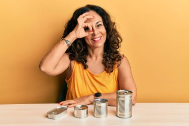 Güzel orta yaşlı bir kadın, konserve yiyeceklerle gülümsüyor, mutlu mesut gülümsüyor. 