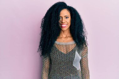 Orta yaşlı Afro-Amerikalı kadın mutlu ve havalı bir gülümseme takınıyor. şanslı kişi. 