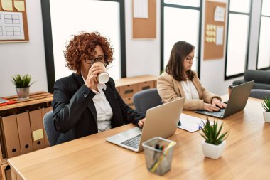 Ofiste çalışan iki kadın grubu. Olgun kadın ve Down sendromlu kız kapsayıcı takım çalışması yapıyor..