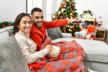 Genç İspanyol çift evdeki Noel ağacının yanında film seyrediyor..