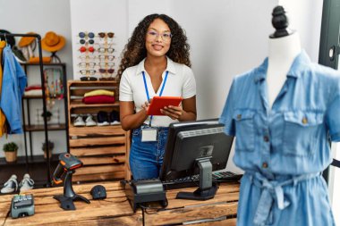 Genç Latin esnaf, giyim mağazasında çalışan dokunmatik ped kullanıyor..