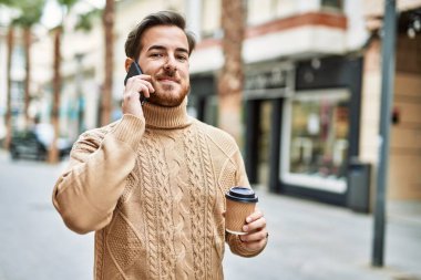 Kafkasyalı genç adam akıllı telefondan konuşuyor. Şehirde kahve içiyor..