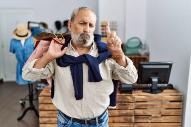 Butik dükkanında alışveriş torbaları tutan yakışıklı bir adam üzgün ve üzgün görünüyor, parmaklarıyla yön gösteriyor, mutsuz ve depresif.. 