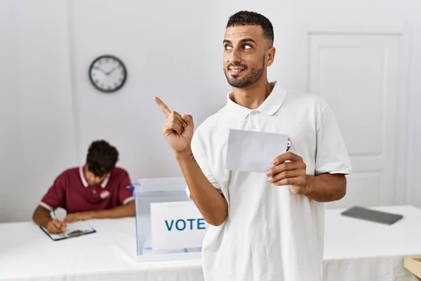 若いですヒスパニック系の男投票箱に包まれて笑顔幸せなポインティングで手と指で側面 — ストック写真
