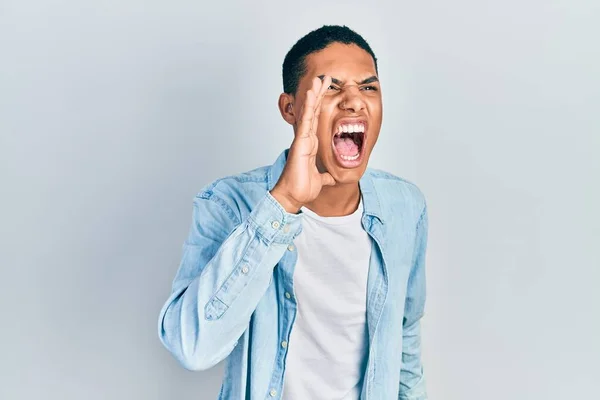 カジュアルな服を着た若いアフリカ系アメリカ人の男が大声で叫び 口の上で手で横に大声で叫んでいる コミュニケーションの概念 — ストック写真