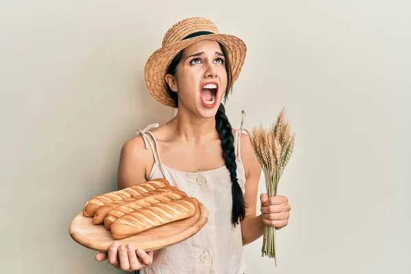 Young Hispanic Woman Holding Homemade Bread Spike Wheat Angry Mad — 스톡 사진