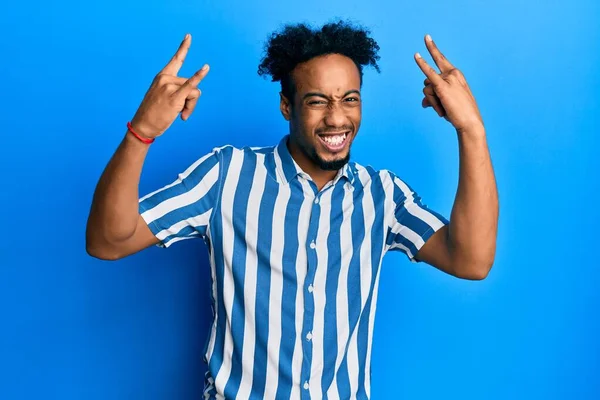 Sakallı, sıradan çizgili tişörtlü, çılgın bir ifadeyle bağıran, elleri havada rock sembolü yapan Afrikalı genç bir Amerikalı. Müzik yıldızı. ağır kavram. 