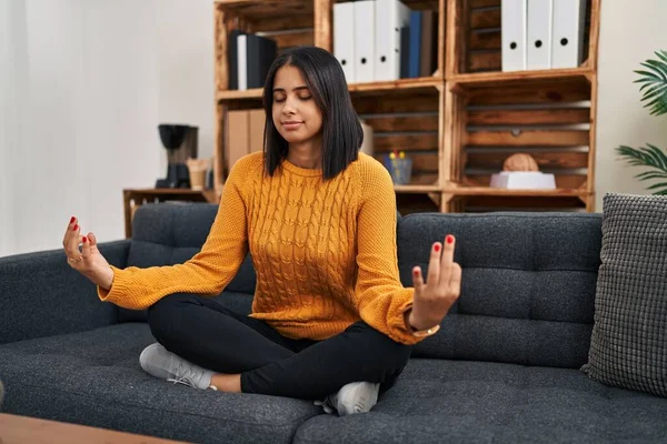 Genç Latin kadın psikoloji hastası klinikte yoga egzersizi yaparken rahatlamış.