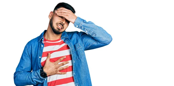 Young Hispanic Man Beard Wearing Casual Denim Jacket Touching Forehead — Φωτογραφία Αρχείου