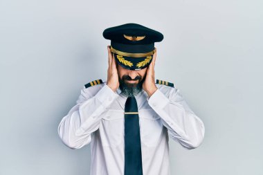 Uçak pilotu üniforması giyen genç İspanyol adam acı ve migren yüzünden çaresiz ve stresli bir baş ağrısı çekiyor. Eller başının üstünde.. 