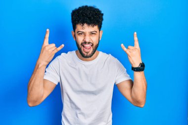 Sakallı, beyaz tişörtlü, çılgın bir ifadeyle bağıran, elleri havada rock sembolü yapan genç bir Arap. Müzik yıldızı. ağır müzik konsepti. 