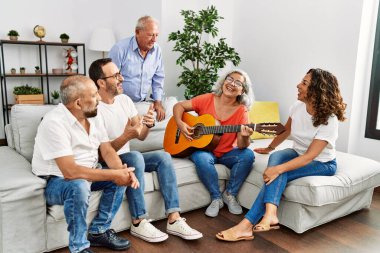 Bir grup orta yaşlı arkadaş evdeki kanepede oturup klasik gitar çalıyorlar..