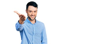 Sıradan bir iş gömleği giymiş, sakallı İspanyol bir adam dostça el sıkışma ve hoş geldin demek için gülümsüyor. başarılı iş. 