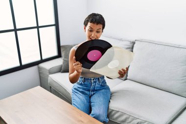 Genç İspanyol kadın gülümsüyor. Elinde vinil disk tutuyor.