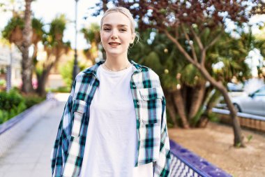 Modern beyaz saç stili ile genç ve güzel bir kadın dışarıda mutlu bir şekilde gülümsüyor.