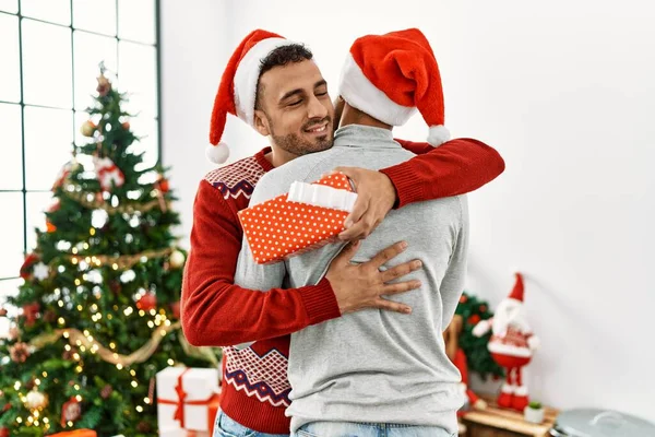 Two Hispanic Men Couple Surprise Gift Standing Christmas Tree Home — Stock Photo, Image