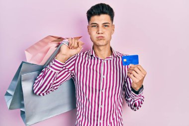 Elinde alışveriş poşetleri ve komik suratlı yanak şişiren kredi kartı kullanan genç bir İspanyol. Ağzı havayla şişer, havayı yakalar.. 