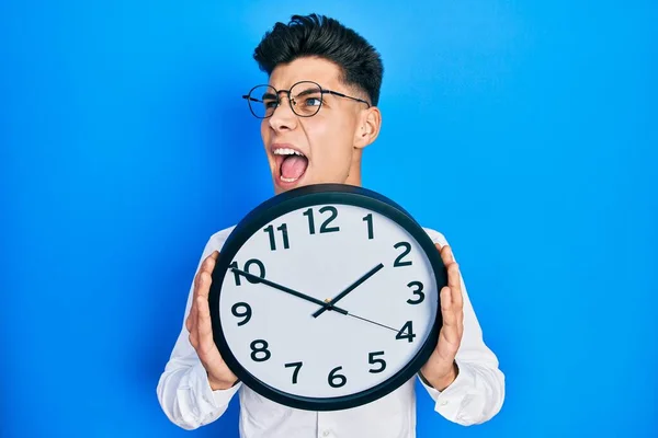 Joven Hombre Hispano Sosteniendo Gran Reloj Cara Enojado Loco Gritando —  Fotos de Stock