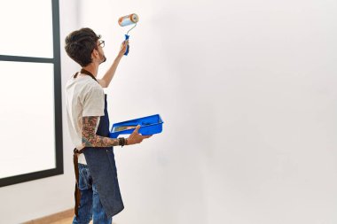 Evdeki silindiri kullanarak duvarı boyayan ressam.