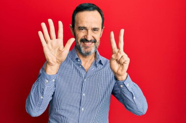 Orta yaşlı İspanyol bir adam gündelik kıyafetler giyer ve yedi numaralı parmaklarını göstererek gülümseyerek mutlu ve kendinden emin bir şekilde gösterir.. 