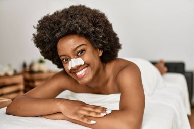 Genç Afrikalı Amerikalı kadın güzellik merkezinde kendine güvenen burun bandı takıyor.