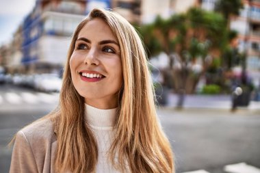 Sokakta kendinden emin gülümseyen genç sarışın kadın