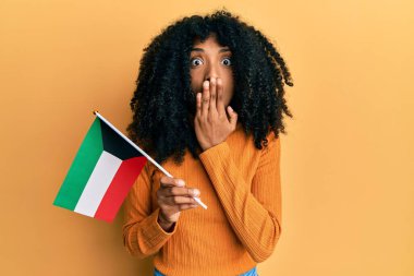 Afro saçlı, kuveyt bayrağı taşıyan, ağzı ağızla kaplanmış, şok olmuş ve hata yapmaktan korkan Afro-Amerikalı bir kadın. şaşırmış ifade 