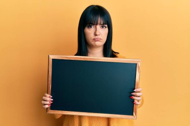 Karatahta tutan genç İspanyol kadın şüpheci ve gergin, sorun yüzünden somurtuyor. negatif kişi. 