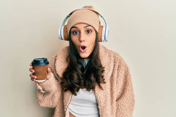 Młoda Latynoska Kobieta Przy Użyciu Słuchawek Pijących Kawę Przerażona Zdumiona — Zdjęcie stockowe
