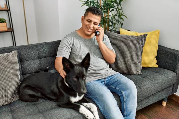 Jovem Hispânico Falando Smartphone Sentado Sofá Com Cão Casa — Fotografia de Stock