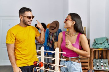 Genç Latin çift gülümseyerek mağazadan güneş gözlüğü seçiyor..