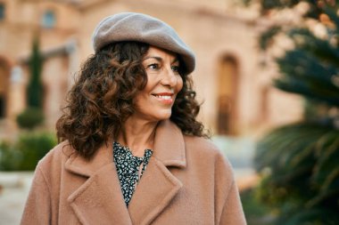 Orta yaşlı İspanyol kadın gülümseyerek şehirde mutlu mesut dikiliyor..